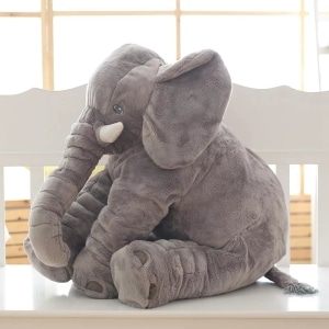 Peluche de un elefante gris sentado. Tiene grandes orejas y colmillos. La felpa de algodón es suave.