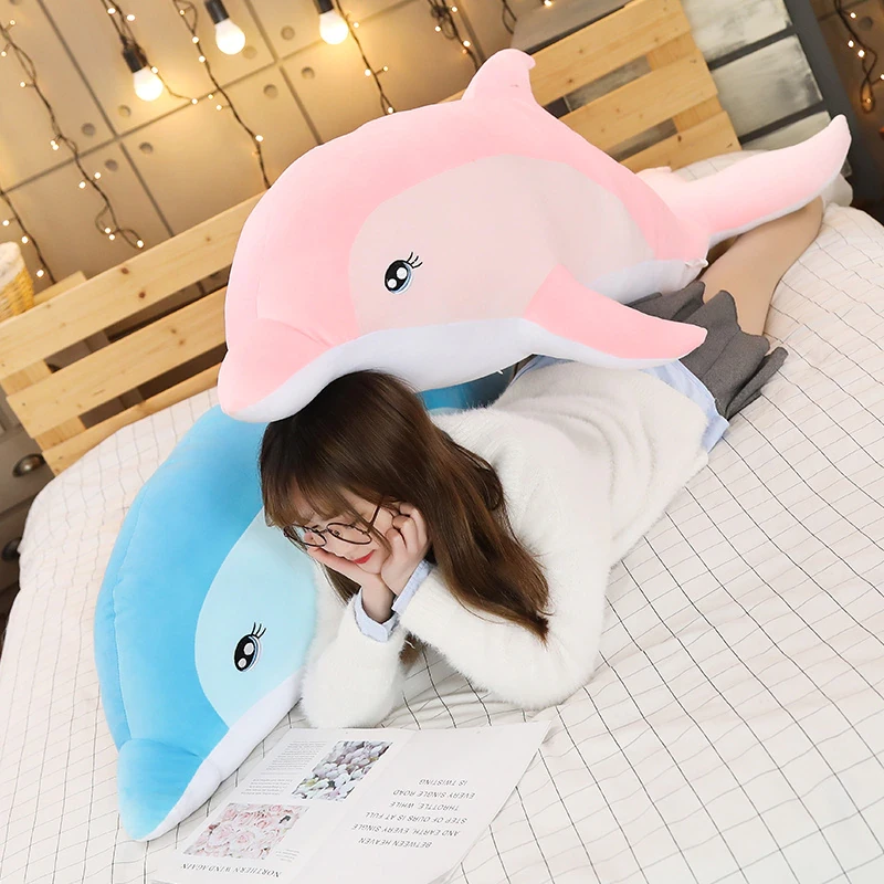 Peluche de delfín para niña en una cama con niña a remolque
