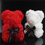 Dos osos de peluche de flores artificiales, uno es rojo y el otro blanco, están en una habitación negra