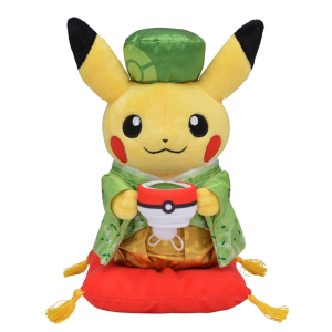 Peluche de Pikachu sosteniendo una pokeball y vistiendo un traje chino verde con un sombrero a juego y de pie sobre un pequeño cojín rojo