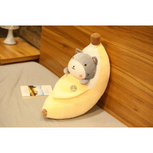 Peluche de plátano pelado con un shiba inu gris dentro sobre una cama gris y una pared color madera con un libro al lado